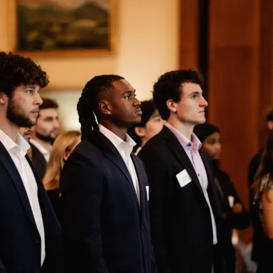 students standing at gathering and looking off camera